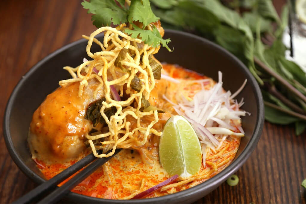 khao soi - a hand sliced rice noodle soup with clear chicken, beef or pork broth topped